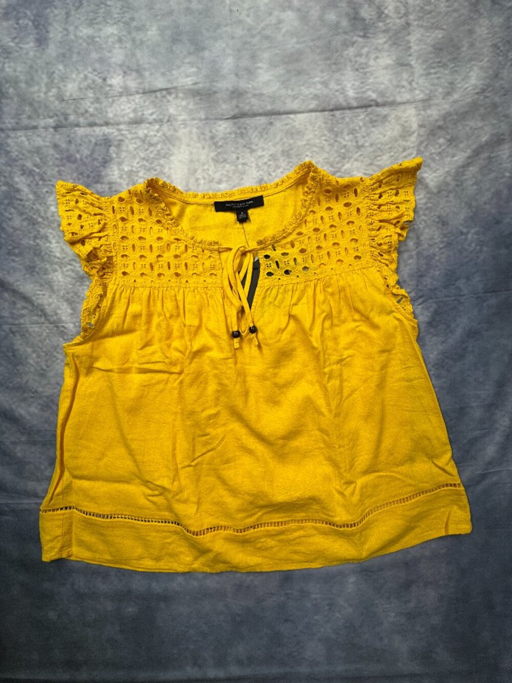 Marc New York yellow eyelet blouse features ruffled cap sleeves and a tassel tie